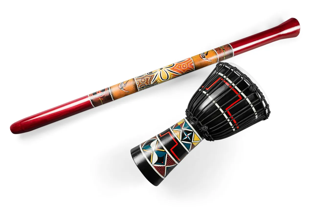 Didgeridoo decorado junto a un tambor djembé sobre fondo blanco