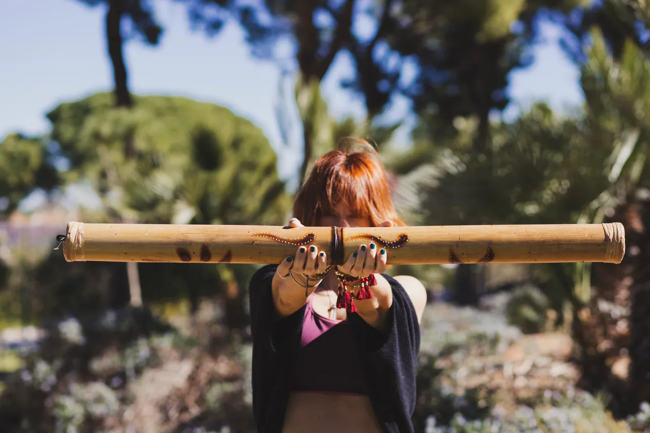 Mujer sosteniendo un didgeridoo de bambú al aire libre
