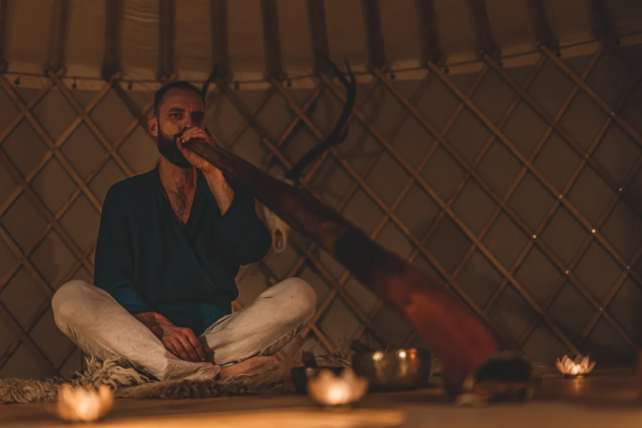 Persona tocando el didgeridoo sentada en un ambiente de meditación